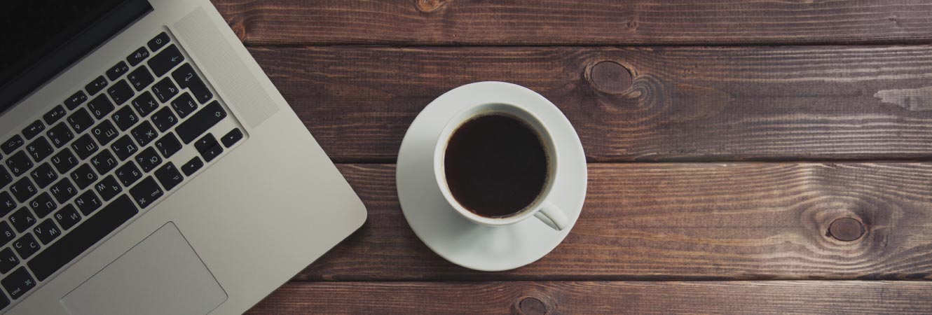 A cup of plain coffee by a laptop on a table