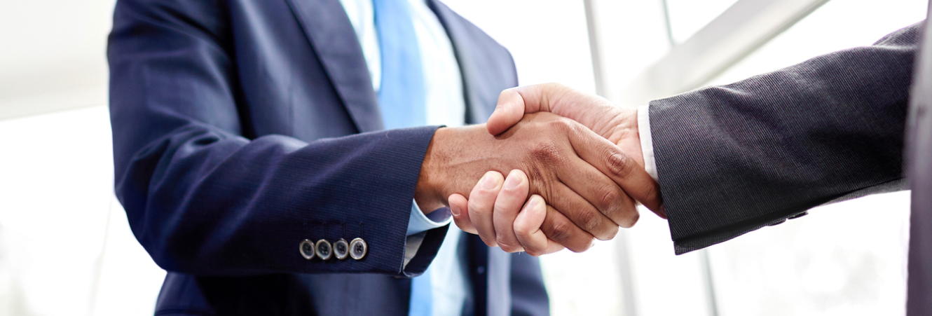 A close up of two suited business men shaking hands