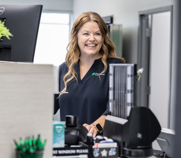 Female retail banker smiles as she works at a computer.