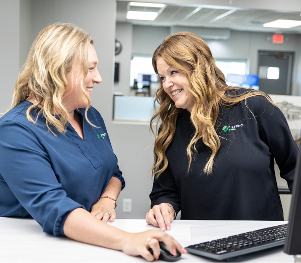Two businesswomen work together at one computer in a bank.