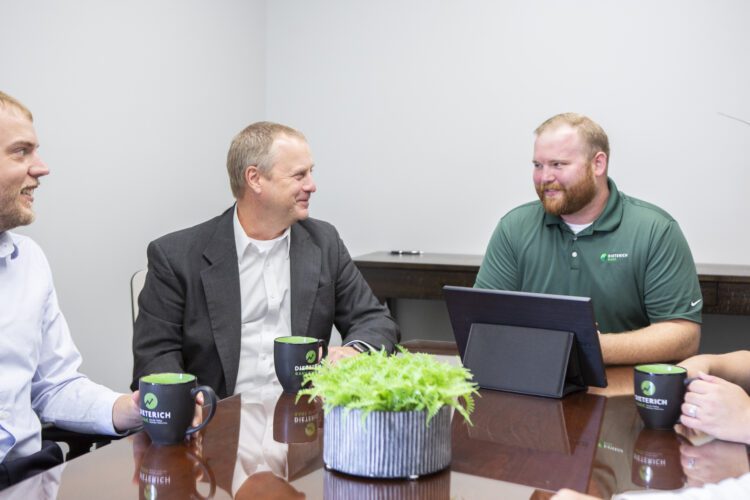 A group of Dieterich Bank lenders sit at a conference table while drinking coffee.