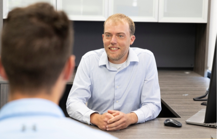 A male business lender sits at his desk helping a male customer.