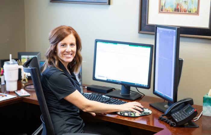 A woman sits at her desk using the mouse of her computer.