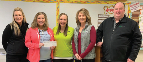 Five Dieterich Bank members in a classroom hold up a charity check made out to a teacher.