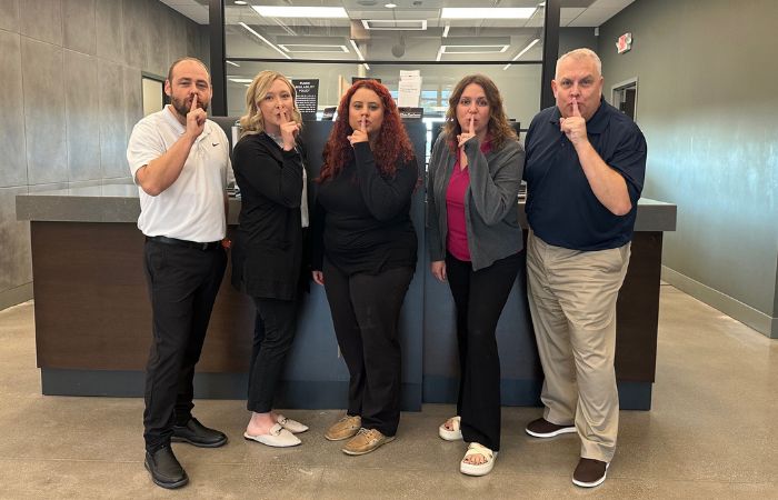 Dieterich Bank Newton Team holding their fingers over their mouth in a shhh motion.