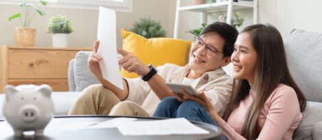 Couple reviewing bank statements at home, piggy bank on the coffee table.